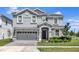 Charming two-story home with manicured lawn, gray facade, arched entryway, and a two car garage at 1533 Flange Dr, Davenport, FL 33896