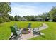 Landscaped backyard with fire pit, green lawn, and view of the house and detached garage at 1550 Bluewater Run, Chuluota, FL 32766