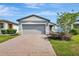 Charming single Gathering home featuring a gray stucco exterior, two-car garage and a brick paver driveway at 29400 Caspian St, Leesburg, FL 34748