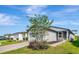 Charming one-story single Gathering home showcasing a stone accentuated facade, gray stucco exterior, and manicured landscaping at 29400 Caspian St, Leesburg, FL 34748