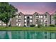 Beautiful exterior view of a waterfront apartment building on a grassy lawn during a colorful dusk at 4740 Walden Cir # 28, Orlando, FL 32811