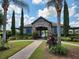 Charming clubhouse entrance with stone facade, blue shutters, and lush landscaping under a bright, cloudy sky at 5107 Appenine W Loop, St Cloud, FL 34771