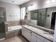 Main bathroom featuring double vanity, granite countertops, soaking tub, glass shower, and modern fixtures at 5107 Appenine W Loop, St Cloud, FL 34771