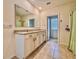 Bathroom with double sinks, granite countertop, large mirror and a doorway to toilet area at 6780 Coral Berry Dr, Mount Dora, FL 32757