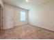A bright bedroom features neutral carpet, white walls, and a window letting in natural light at 6780 Coral Berry Dr, Mount Dora, FL 32757