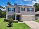 Two-story home featuring solar panels, dark shutters, a two-car garage, and a well-maintained lawn at 6780 Coral Berry Dr, Mount Dora, FL 32757