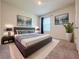 Staged bedroom with a gray bed, accent paintings, and bright natural light at 6780 Coral Berry Dr, Mount Dora, FL 32757