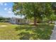 Spacious, sunny yard with mature trees and a view of the home's front exterior, showcasing its curb appeal at 7701 Cassino Ave, Orlando, FL 32819