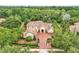 Stunning aerial view of the home showcasing its clay tile roof, brick-paved driveway, manicured landscaping, and lush surrounding greenery at 9729 Lake Hugh Dr, Gotha, FL 34734