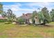 Beautiful backyard featuring a manicured lawn, vibrant landscaping, mature trees, and a putting green, perfect for outdoor enjoyment at 9729 Lake Hugh Dr, Gotha, FL 34734
