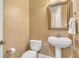 Bathroom features decorative wallpaper, pedestal sink, toilet, and framed mirror at 9729 Lake Hugh Dr, Gotha, FL 34734