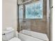 Bathroom features glass enclosed shower/tub, tiled walls, window, toilet, and towel rack at 9729 Lake Hugh Dr, Gotha, FL 34734