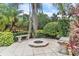 Backyard fire pit area with stone benches, surrounded by lush landscaping, perfect for evening gatherings at 9729 Lake Hugh Dr, Gotha, FL 34734