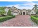 Elegant home with a large brick driveway, manicured landscaping, and a three-car garage at 9729 Lake Hugh Dr, Gotha, FL 34734