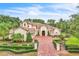 Beautiful stucco home featuring a brick-paved driveway and walkway lined with manicured landscaping and a black wrought iron fence at 9729 Lake Hugh Dr, Gotha, FL 34734