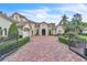 Charming home with a brick driveway, manicured landscaping, wrought iron gates, and a three-car garage at 9729 Lake Hugh Dr, Gotha, FL 34734