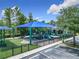 A colorful playground is pictured with a protective blue canopy, surrounded by a black fence and ample parking at 10875 Arbor View Blvd, Orlando, FL 32825