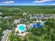 Aerial view of a community pool featuring a large pool deck, ample lounge seating, and blue sun shades in a lush neighborhood at 10875 Arbor View Blvd, Orlando, FL 32825