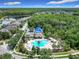 Aerial view of a community pool featuring a large pool deck, ample lounge seating, and blue sun shades in a lush neighborhood at 10875 Arbor View Blvd, Orlando, FL 32825