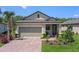 Charming home featuring a brick driveway, attached garage, and well-manicured lawn with colorful flowers at 1392 Lombardi Ct, Kissimmee, FL 34759