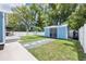 Landscaped backyard featuring a charming shed with gray stone pathway, and a white privacy fence at 141 W Main St, Lake Helen, FL 32744