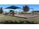 Community playground with swings, slide, and shade covering, surrounded by grassy area at 228 Primrose Dr, Davenport, FL 33837