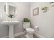 Clean half bathroom featuring a pedestal sink, toilet and decorative plants with neutral wall decor at 2342 Clemblue Rd, Clermont, FL 34715