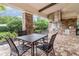 Covered outdoor kitchen with a stone surround, stainless steel grill, ceiling fan, and patio dining table at 2342 Clemblue Rd, Clermont, FL 34715