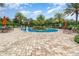 A circular zero entry community pool is accented by palm trees, lounge chairs and lush landscaping at 2342 Clemblue Rd, Clermont, FL 34715