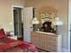 Bright main bedroom with natural wood dresser and three pictures hung above and a white entry door at 2808 Manatee Rd, Tavares, FL 32778