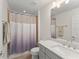 Bright bathroom with a modern vanity, framed mirror, and a tiled shower featuring a neutral-toned shower curtain at 390 Anessa Rose Loop, Ocoee, FL 34761