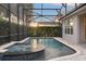 Backyard pool with an attached spa and enclosed lanai, surrounded by lush greenery and brick pavers at 390 Anessa Rose Loop, Ocoee, FL 34761
