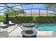 Screened-in pool and spa with a fire pit and lounge chairs, perfect for outdoor relaxation and entertaining at 390 Anessa Rose Loop, Ocoee, FL 34761