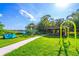 Community playground featuring swings, a slide, and other play equipment on a well-maintained green lawn under a blue sky at 458 Meadowood Blvd, Fern Park, FL 32730