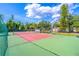 Well-maintained red and green tennis court surrounded by fencing and lush greenery, perfect for recreational games at 458 Meadowood Blvd, Fern Park, FL 32730