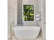 Freestanding tub with chrome faucet, gray curtains, and a wall mounted towel rack and view to backyard at 5157 Latrobe Dr, Windermere, FL 34786