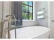 Freestanding tub next to a window with backyard view and stylish grey draperies and wall mounted towel rack at 5157 Latrobe Dr, Windermere, FL 34786