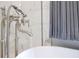 Close up of a stylish freestanding tub with a chrome faucet, grey draperies, and view to the backyard at 5157 Latrobe Dr, Windermere, FL 34786