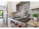 Close up on modern range, custom backsplash, and granite countertops in the kitchen at 5157 Latrobe Dr, Windermere, FL 34786