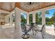 Covered outdoor dining area with travertine floors and stylish furniture next to an outdoor kitchen and overlooking the pool at 5157 Latrobe Dr, Windermere, FL 34786