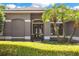 Close-up of front entrance showing double doors framed by palm trees and manicured hedges at 5335 Bay Side Dr, Orlando, FL 32819