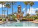 A pool with a water slide, palm trees and a lighthouse structure under a clear blue sky at 5944 Lake Melrose Dr, Orlando, FL 32829