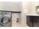 Laundry room featuring modern gray washer and dryer, ample counter space, and stylish wallpaper at 7184 Enchanted Lake Dr, Winter Garden, FL 34787