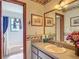 Bathroom vanity with basin sink, framed mirrors, floral wallpaper border and view of white tiled shower and tub at 750 Sw 91St Pl, Ocala, FL 34476