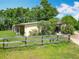 Exterior view of a rural property featuring lush greenery, mature trees, and wooden fence at 750 Sw 91St Pl, Ocala, FL 34476