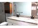 Well-lit bathroom features double sinks with granite countertop, shower, toilet, mirror and wooden storage unit at 104 Oaks Ct, Sanford, FL 32771