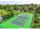 Aerial view of a tennis court with green surface, surrounded by lush landscaping and a lake view at 1203 Stone Harbour Rd, Winter Springs, FL 32708