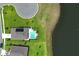 Aerial view captures a home's backyard oasis featuring a pristine pool, solar panel, patio, and manicured landscaping near lake at 1313 Middle Lake Dr, Ormond Beach, FL 32174