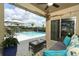 Cozy covered patio with a wicker sofa overlooking a private pool at 1313 Middle Lake Dr, Ormond Beach, FL 32174