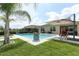 Beautiful pool with an umbrella, fire pit, and palm tree in the backyard for relaxing and entertaining at 1313 Middle Lake Dr, Ormond Beach, FL 32174